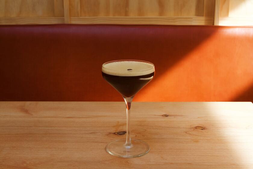 A nonalcoholic espresso martini adorned with a layer of foam and an espresso bean on a wood table at Highly Likely